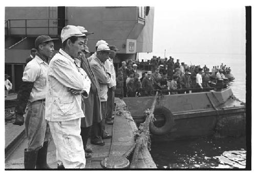 Men watching U.S. Army tugboat being raised