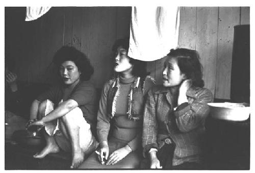 Three women sex workers wearing makeup and Western clothing, one with cigarette