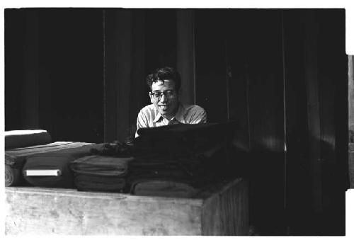 Man sitting behind table covered in bolts of cloth