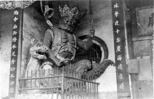 Statue on building of a crowned man on a dragon