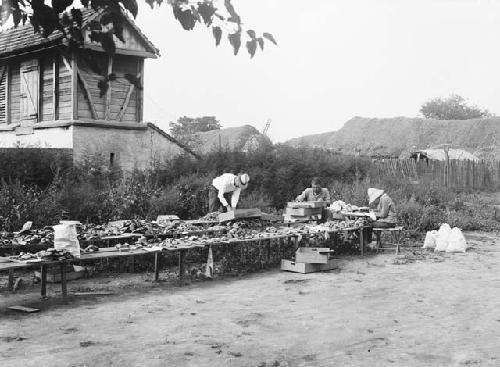 Men bagging up excavated material in the yard of the fieldhouse