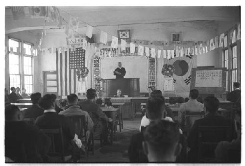 Man at podium speaking to a group at U.S. Information Centre, Tong Yung