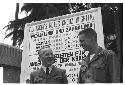 Two men standing in front of a sign