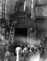 People watching man on ladder against a building