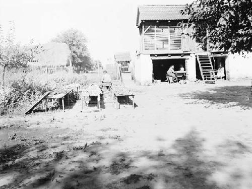 Man sorting materials on tables in field house yard