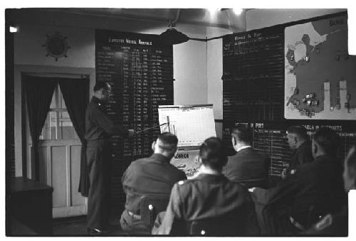 American military personnel reviewing port and cargo charts; central chart reads: "PERCENTAGE OF CARGO HANDLED BY 7TH TMP / 1953-1954"