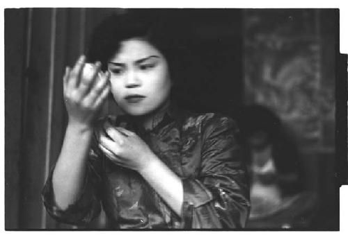 Young woman checking makeup in handheld mirror