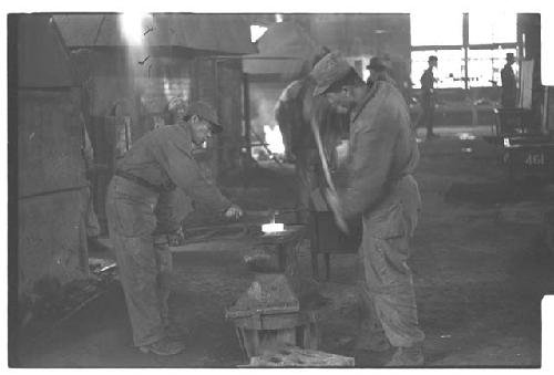 Workers using anvil to work metal