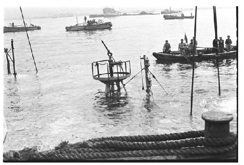 Men on small boat approaching submerged U.S. Army tugboat