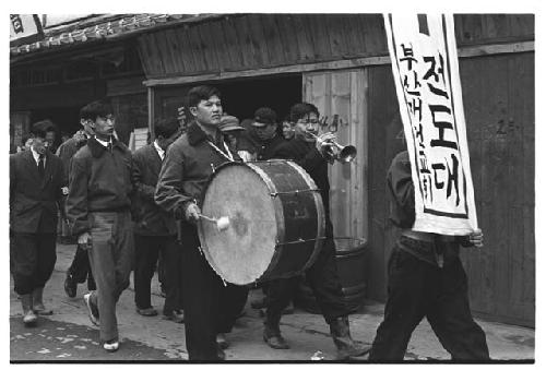 Korean Christian Evangelist band marching down street, banner reads: "Evangelistic Band: the Pusan Reconstruction Church"