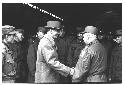 Colonel Slezak and General Whitcomb shaking hands while surrounded by military personnel