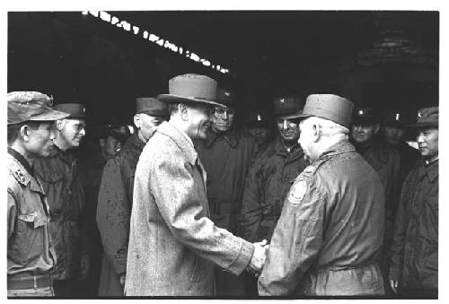 Colonel Slezak and General Whitcomb shaking hands while surrounded by military personnel