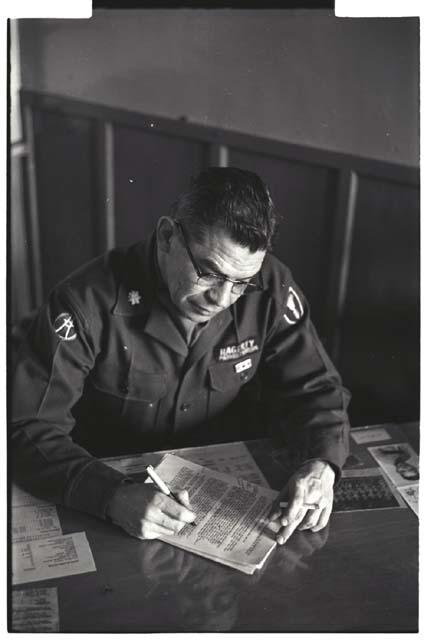 Portrait of Colonel Hagerty looking through document