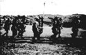 Soldiers marching through field with guns on their shoulders