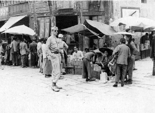 Man in uniform on street with market