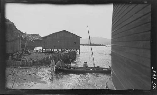 People in canoe next to huts