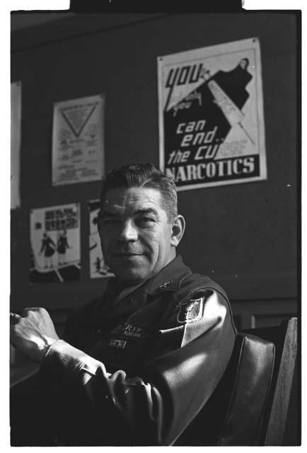 Colonel Hagerty posing in front of a anti-narcotics poster