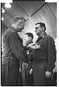 Man looking at another soldier's medal