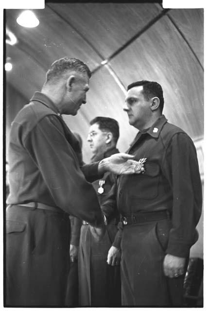 Man looking at another soldier's medal