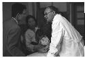 Doctor engaging in conversation with a man, woman and child in background