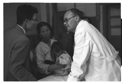 Doctor engaging in conversation with a man, woman and child in background