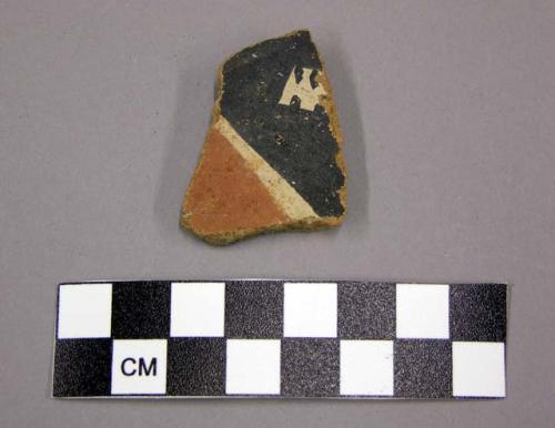 Polychrome body sherd with orange and black linear design on cream slip