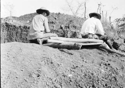 Two men showing method 1 of screening or sifting grave fill