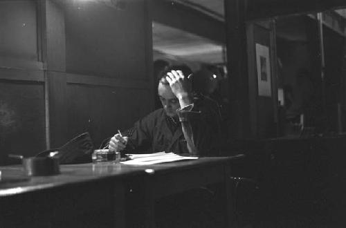 Military man with pen in hand sitting at desk.