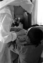 Nun looking at young child's finger over bowl.