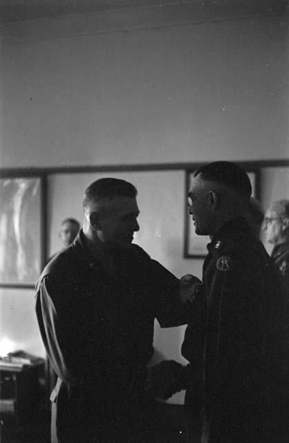 Two military men shaking hands at medal ceremony.