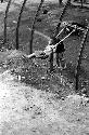 Boy on rope swing, another boy beside him; industrial area.