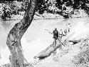 Man pole canoing across Utua in dugout canoe