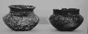 Two small black vessels with human face