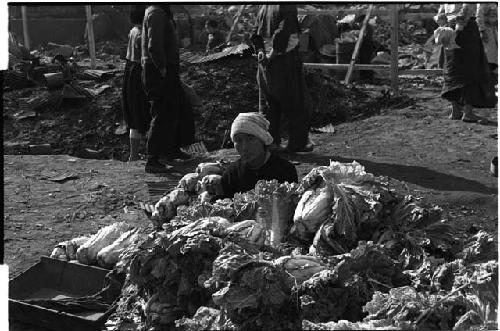 Woman sitting behind a pile of vegetables