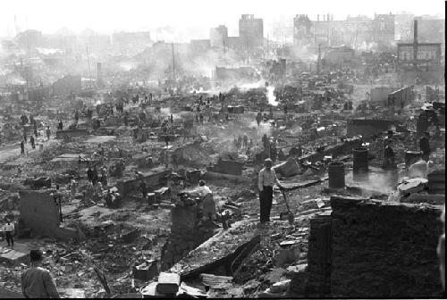 man in white shirt and other people smoky buildings in background