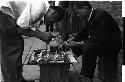 two men bent over a small table on a street