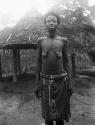 Woman in front of hut, frontal view