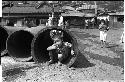 Small child squatting inside long hollow cylinder