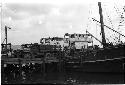 Truck at the end of a pier and a ship resting next to the pier