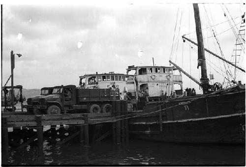 Truck at the end of a pier and a ship resting next to the pier