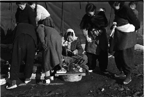 Woman sitting on the ground and some people around her