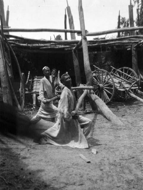 Making cart wheels near Aksu, two men working on a wheel