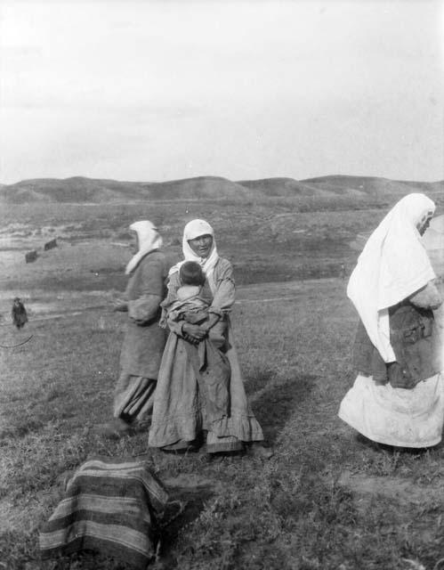 Three women and one child standing in a meadow