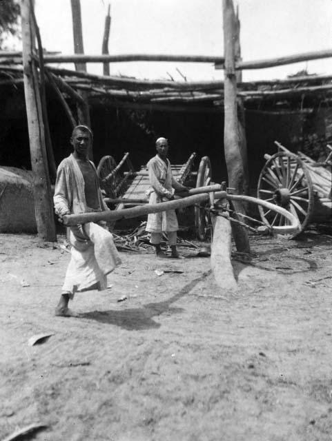 Making cart wheels near Aksu, two men working on a wheel