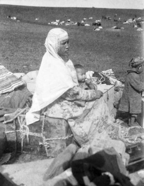 Kazak woman sitting on pile of large bundles