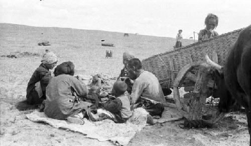 Group of Chahar pilgrims eating by oxcart