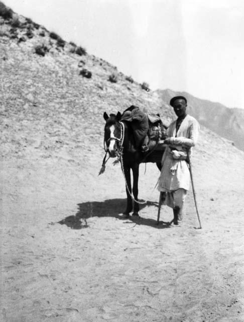 Chuchu Davan (Dawan), Lame Kirghiz, man with crutches standing next to horse
