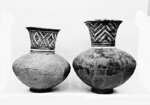 Two red jars with ring bases and flaring polychrome necks, cache 5