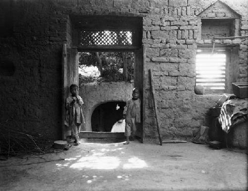 Children in home, boys standing in doorway of large room