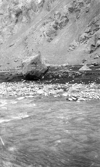 Rocks at base of a large hill, running water